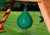 Lifestyle shot of green punching ball hanging from wooden playset.