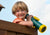 Boy smiling while holding the green and yellow Telescope w/ Compass  from Gorilla Playsets.